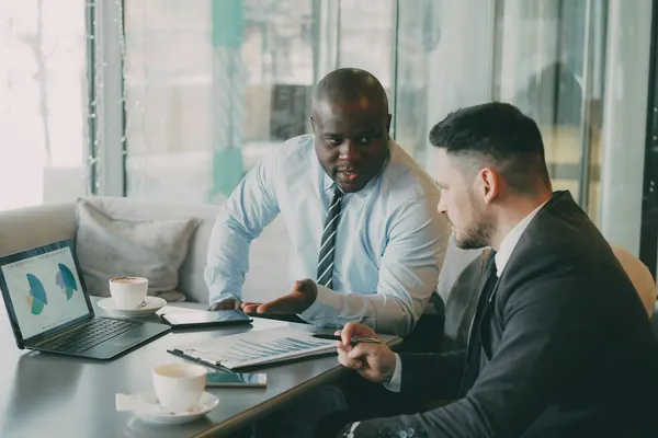 Two business owners comparing IT support costs on a laptop during a meeting