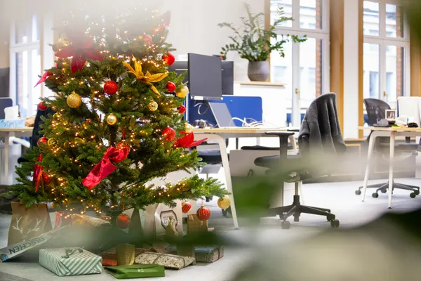 Decorated holiday tree beside empty desks in a quiet office during a seasonal closure